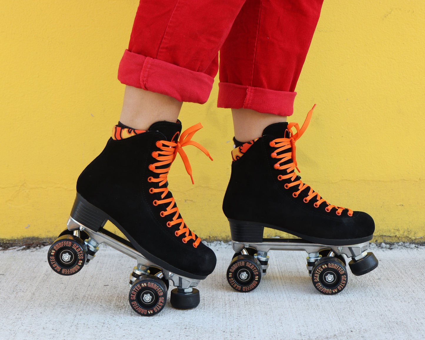 Chuffed Skates black roller skates with yellow wall behind 