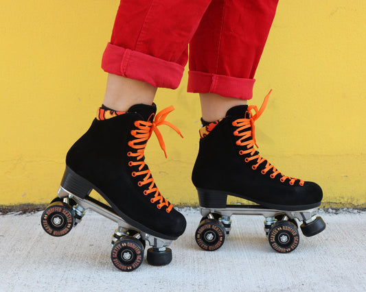 Chuffed Skates black roller skates with yellow wall behind 