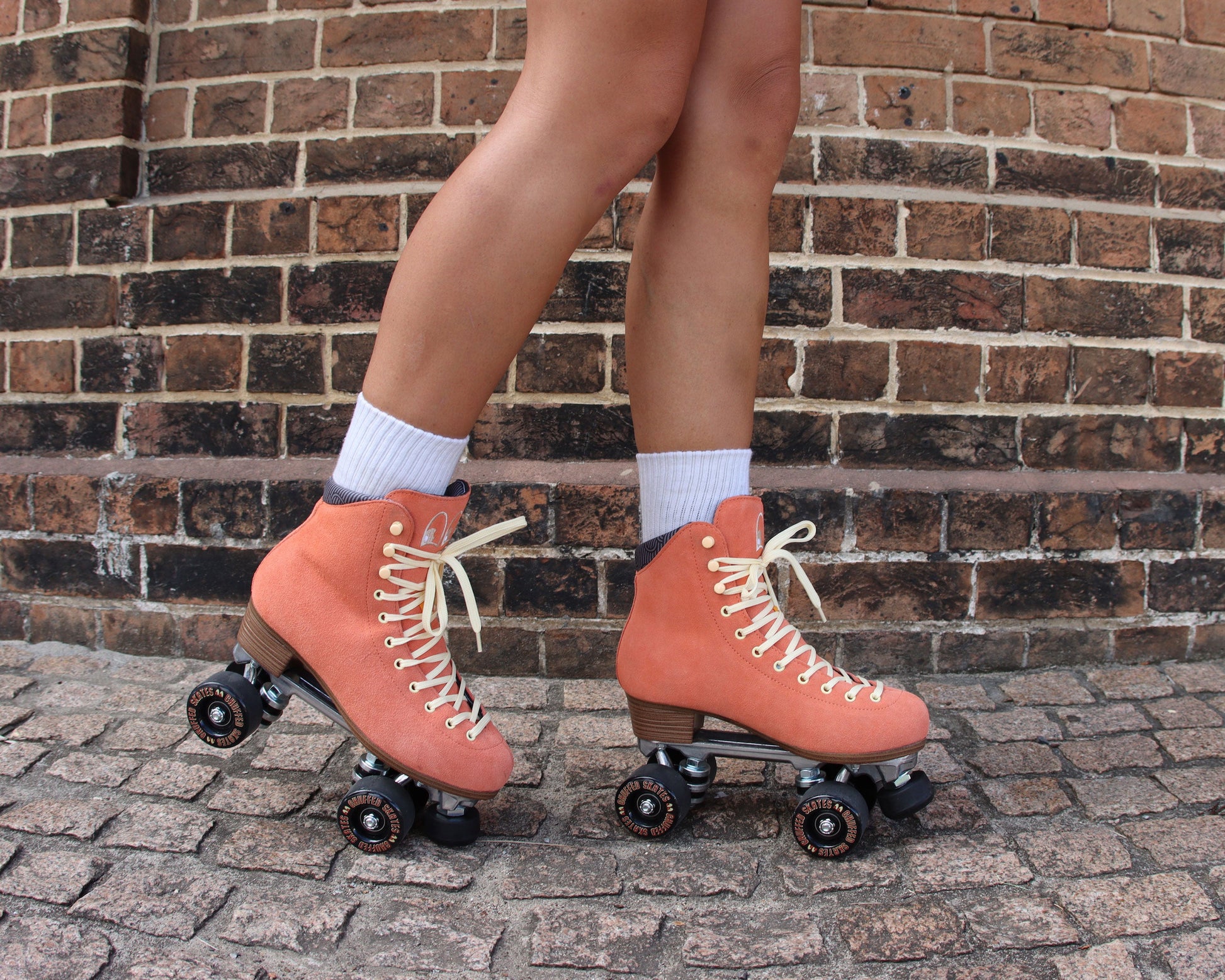 Chuffed Skates peach pink roller skates with brick background